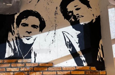 Mural em dois andares na Barbearia Tarantino com pinturas que celebram os filmes clássicos e personagens marcantes de Quentin Tarantino.
